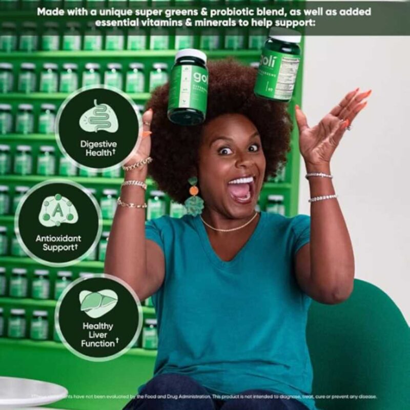 Mujer feliz sosteniendo frascos de Goli Supergreens frente a una pared de productos, señalando beneficios digestivos y antioxidantes.