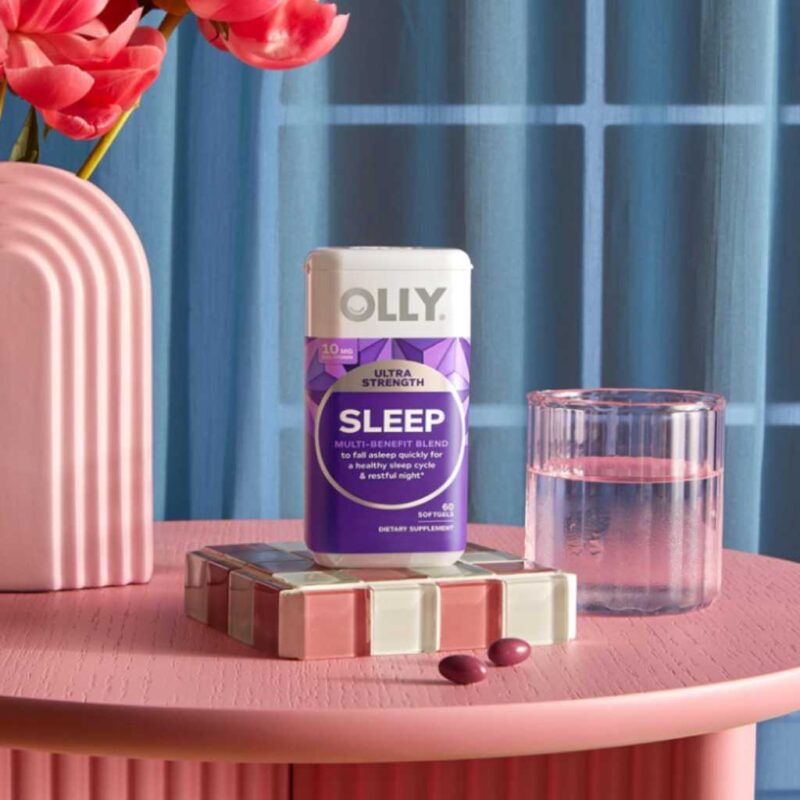 Escena nocturna con OLLY Sleep sobre mesa, cápsulas y vaso de agua